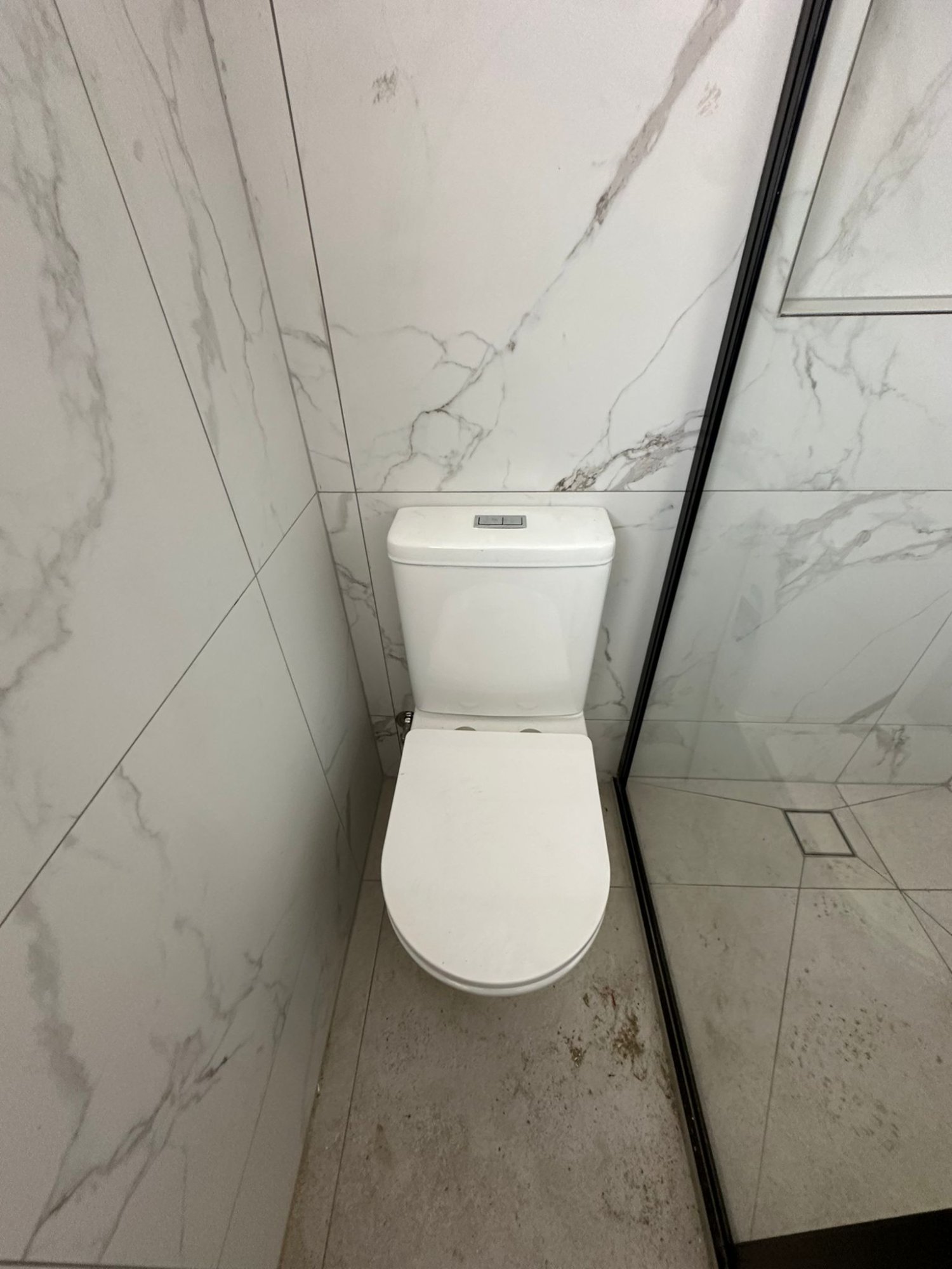 Modern toilet installed against marble feature tile